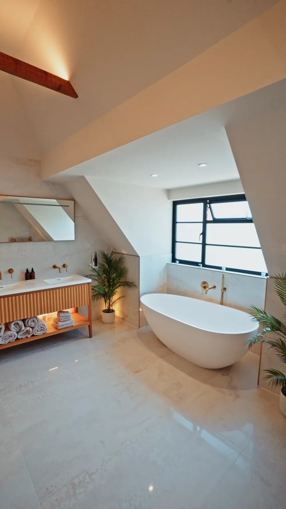 A loft en suite with a freestanding bath and timber vanity