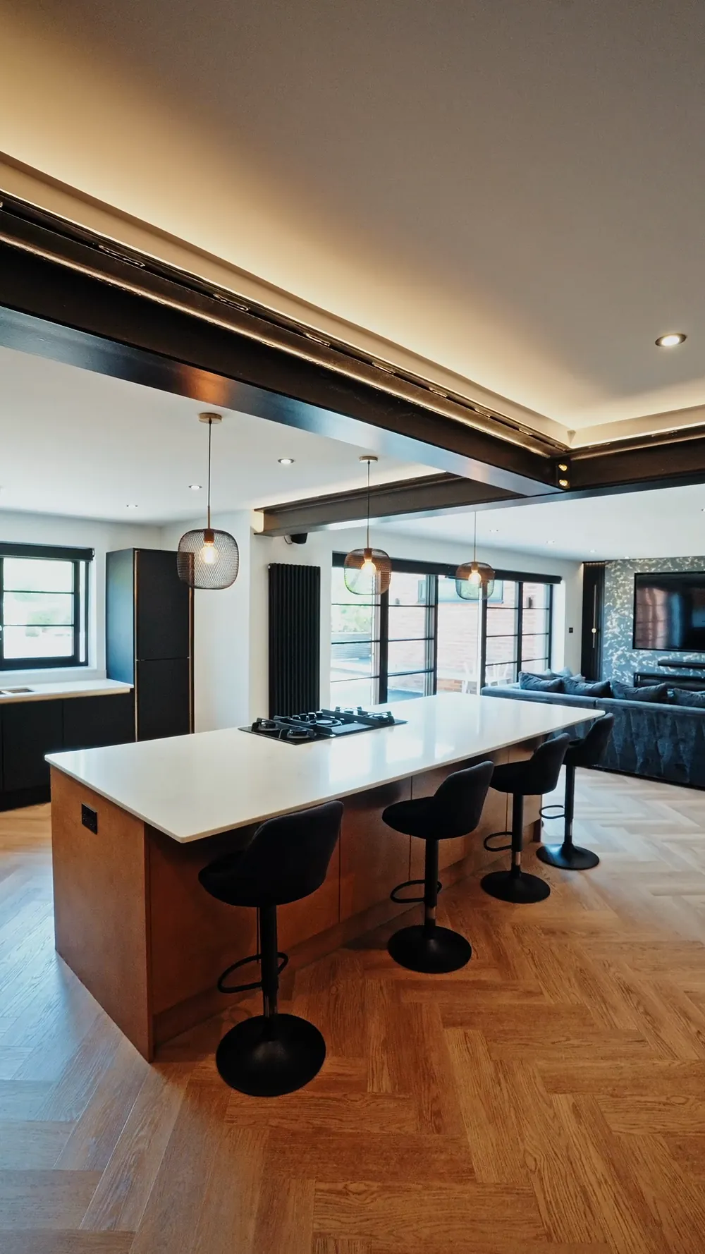 An open plan kitchen with exposed steels and a herringbone floor, renovated by Build and Co